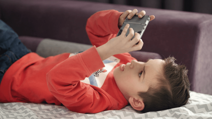 Playing phone mobile kid child game boy using gaming video smartphone stock sofa preschooler